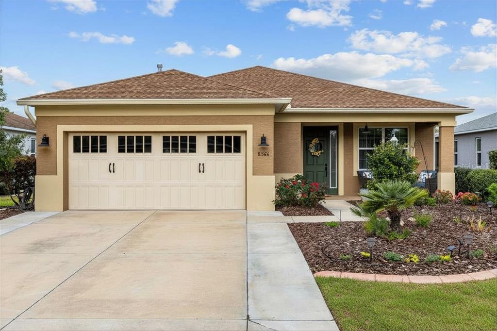 A single-story house with a tan stucco exterior, a two-car garage, and a front porch — 8566 SW 79TH AVENUE, OCALA, FL
