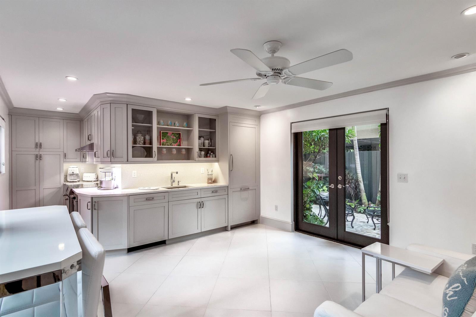 A kitchen with light gray cabinets, white countertops, and glass doors opening to a patio — 226 Chilean Avenue # 4, Palm Beach FL 33480, PALM BEACH, FL