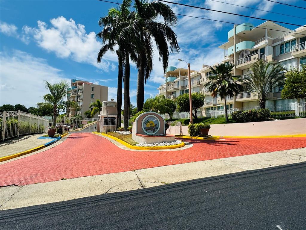 A paved entrance with a central sign and palm trees leads to a residential complex — COND. VILLAS DEL FARO 5015 PUNTA TUNA ST. UNIT 406, MAUNABO, PR