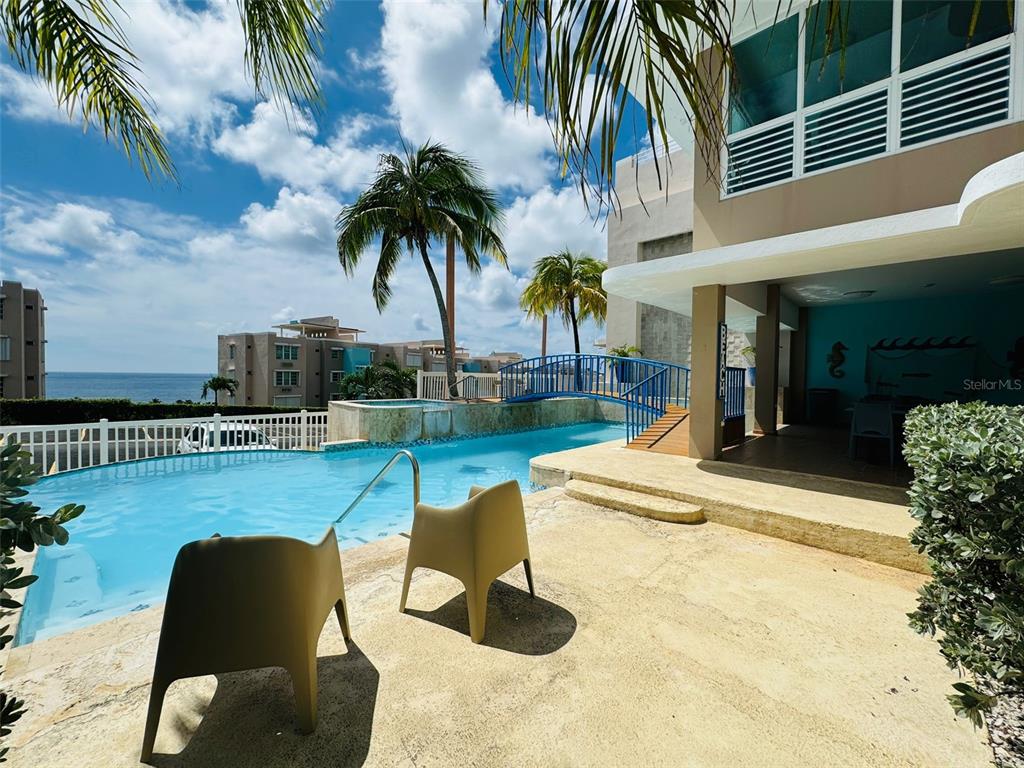 A swimming pool with a small bridge sits on a patio overlooking the ocean — COND. VILLAS DEL FARO 5015 PUNTA TUNA ST. UNIT 406, MAUNABO, PR