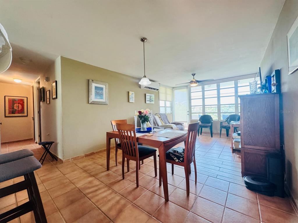 A dining area with a wooden table and chairs sits on tiled floors near a sunroom — COND. VILLAS DEL FARO 5015 PUNTA TUNA ST. UNIT 406, MAUNABO, PR