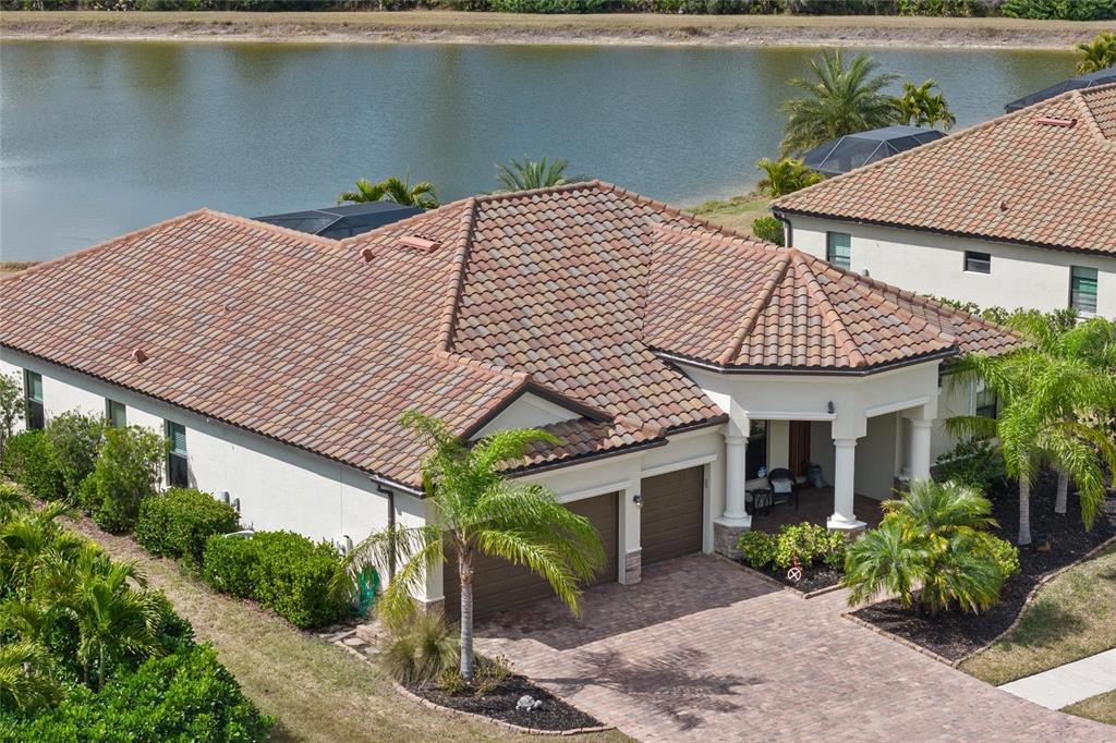 An aerial view of a house with a tiled roof, garage, and a waterfront backyard — 20655 VALPRATO COURT, VENICE, FL