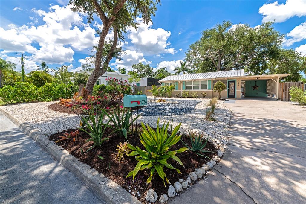 A single-story house with a metal roof, carport, and landscaped front yard with a mailbox — 1034 N 22ND STREET, SARASOTA, FL