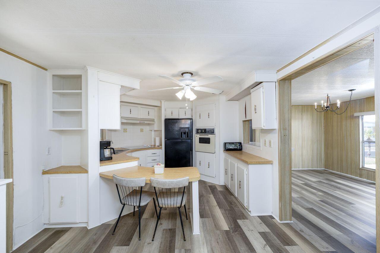 A kitchen features white cabinets, wood-look laminate countertops, a breakfast bar, and wood-patterned flooring — 2001 N 83rd Ave Avenue N # 1281, FL 33702, FL