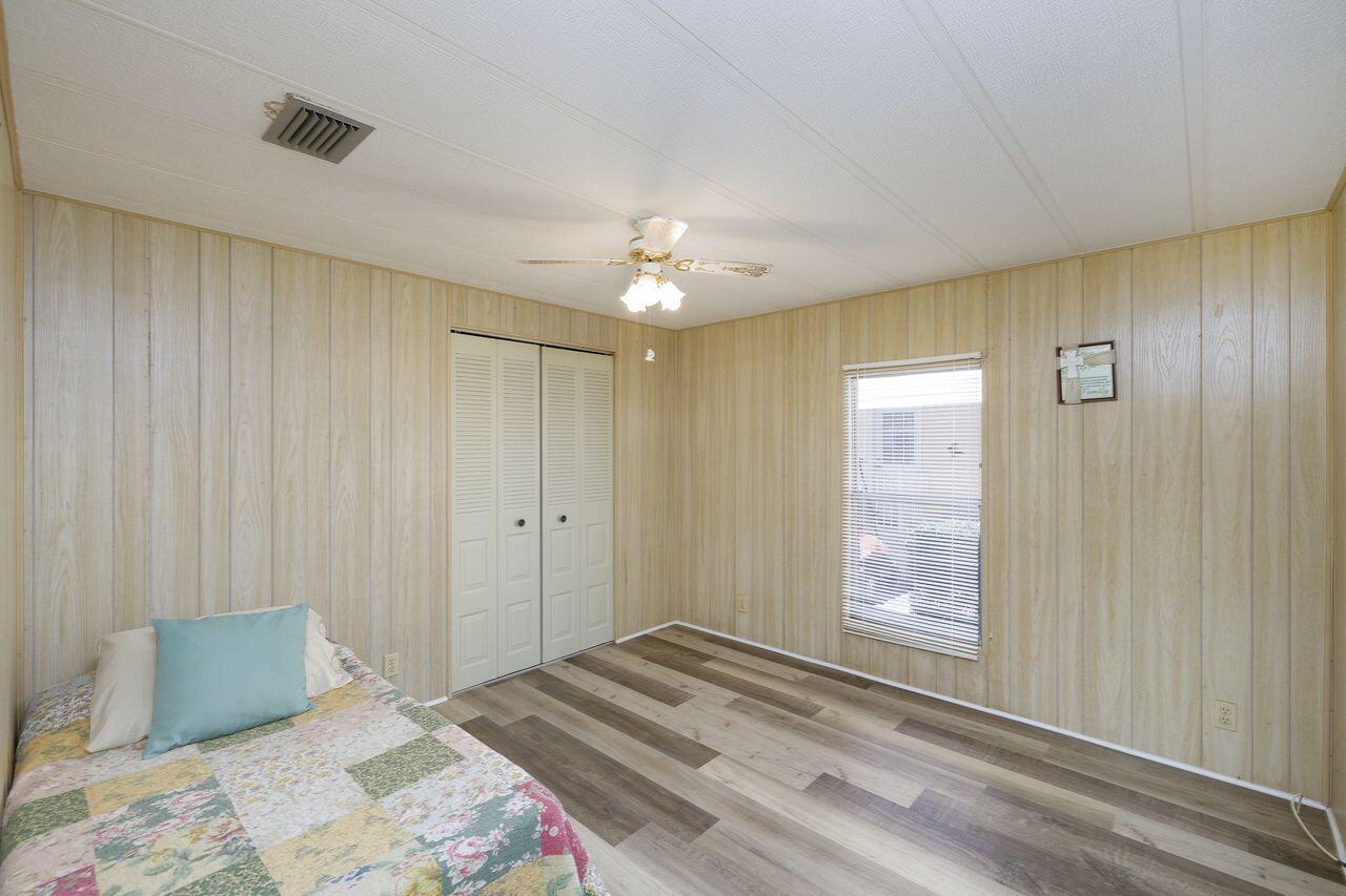 A bedroom with wood-paneled walls, a ceiling fan, a closet, and wood-look flooring — 2001 N 83rd Ave Avenue N # 1281, FL 33702, FL