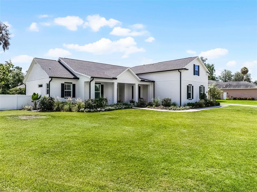 A white, single-story house with a dark roof and black window shutters sits on a lawn — 926 JOHN CRESSLER DRIVE, SEFFNER, FL