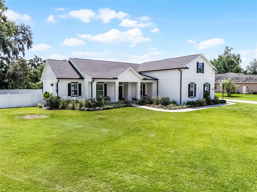 A white, single-story house with black shutters and a dark roof sits on a lawn — 926 JOHN CRESSLER DRIVE, SEFFNER, FL