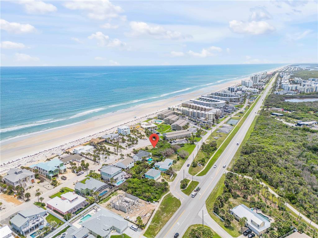 An aerial view shows a coastal neighborhood with houses, a road, and the ocean — 4732 VAN KLEECK DRIVE, NEW SMYRNA BEACH, FL