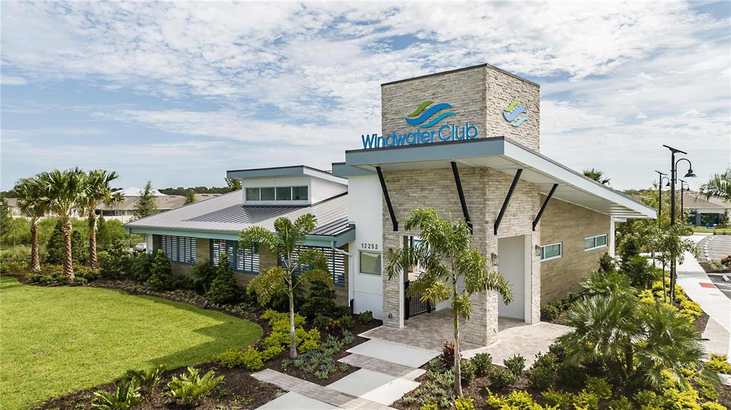The exterior of a modern clubhouse features stone siding, a metal roof, and palm trees — 12324 49TH STREET E, PARRISH, FL