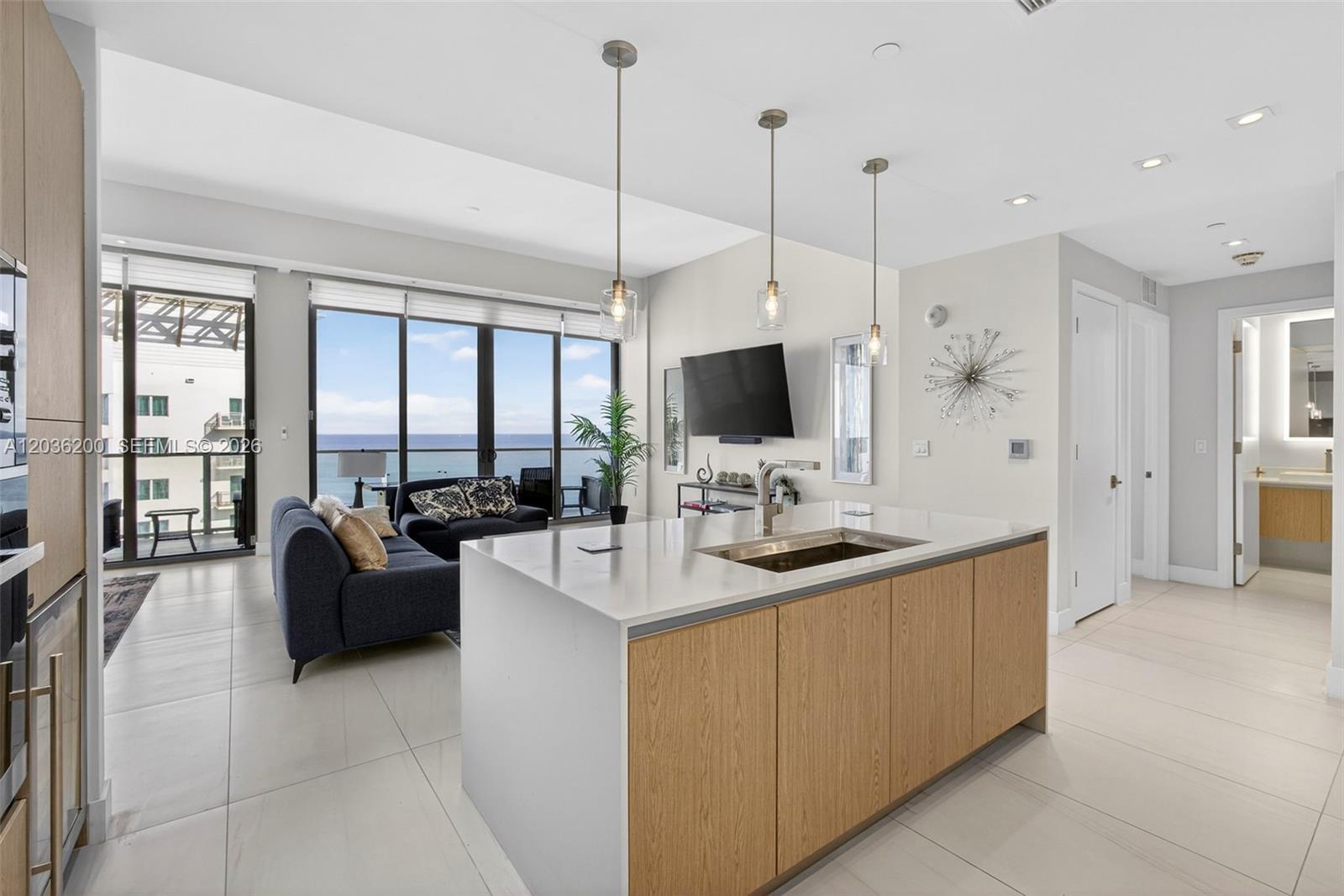A modern kitchen island with a sink sits in an open-concept living area with ocean views — 3100 N Ocean Dr # 1801, Singer Island FL 33404, SINGER ISLAND, FL