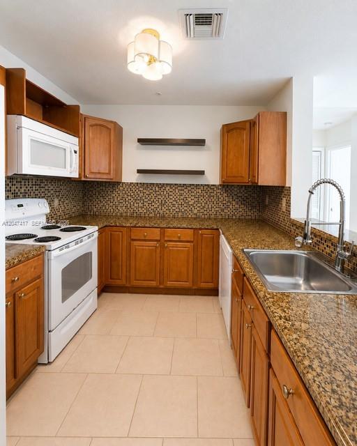 A kitchen features wood cabinets, granite countertops, a white stove, and a tiled backsplash — 1203 Town Center # 314, Jupiter FL 33458, JUPITER, FL