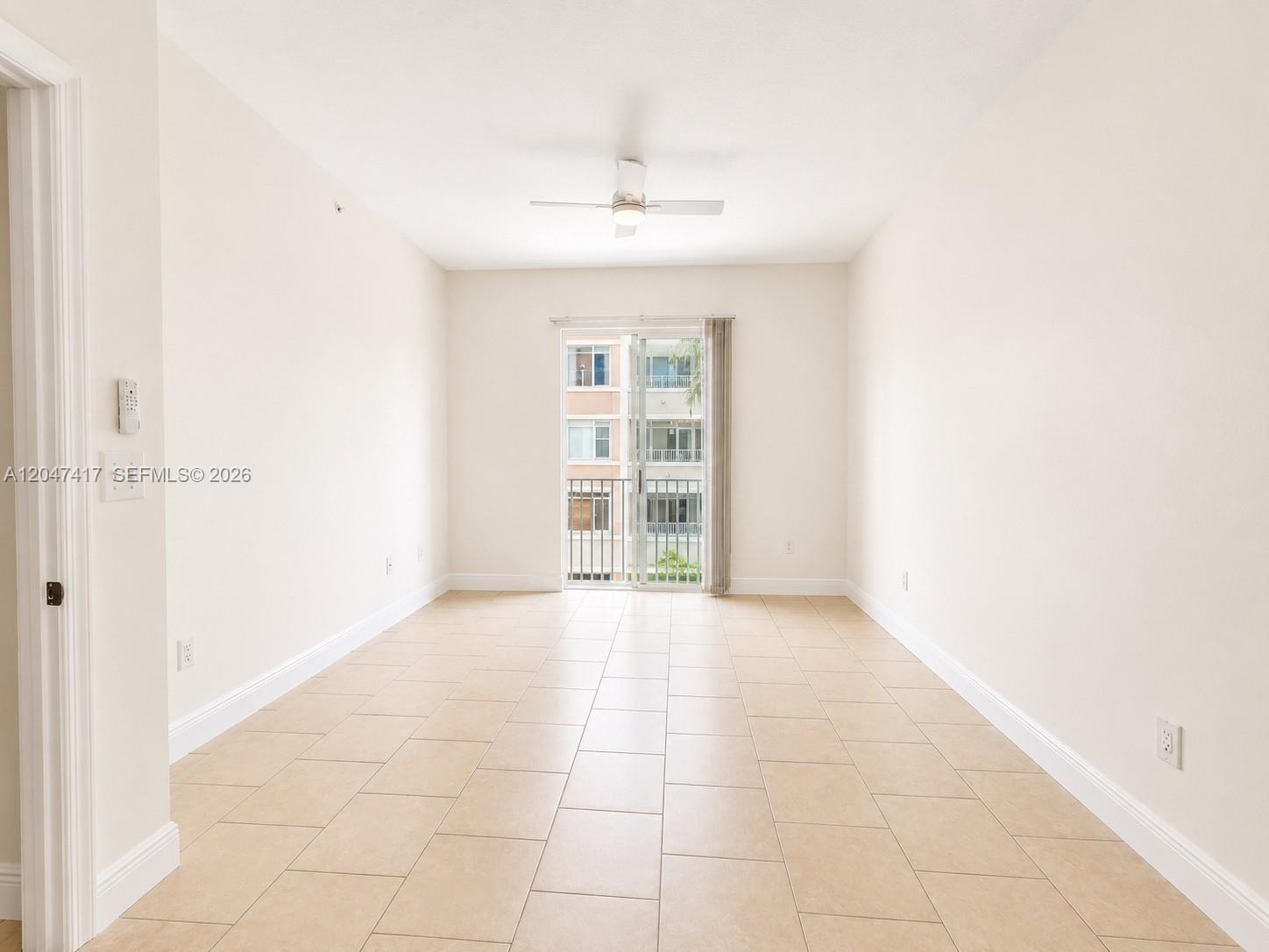An empty room features beige tile flooring, white walls, a ceiling fan, and a sliding glass door — 1203 Town Center # 314, Jupiter FL 33458, JUPITER, FL