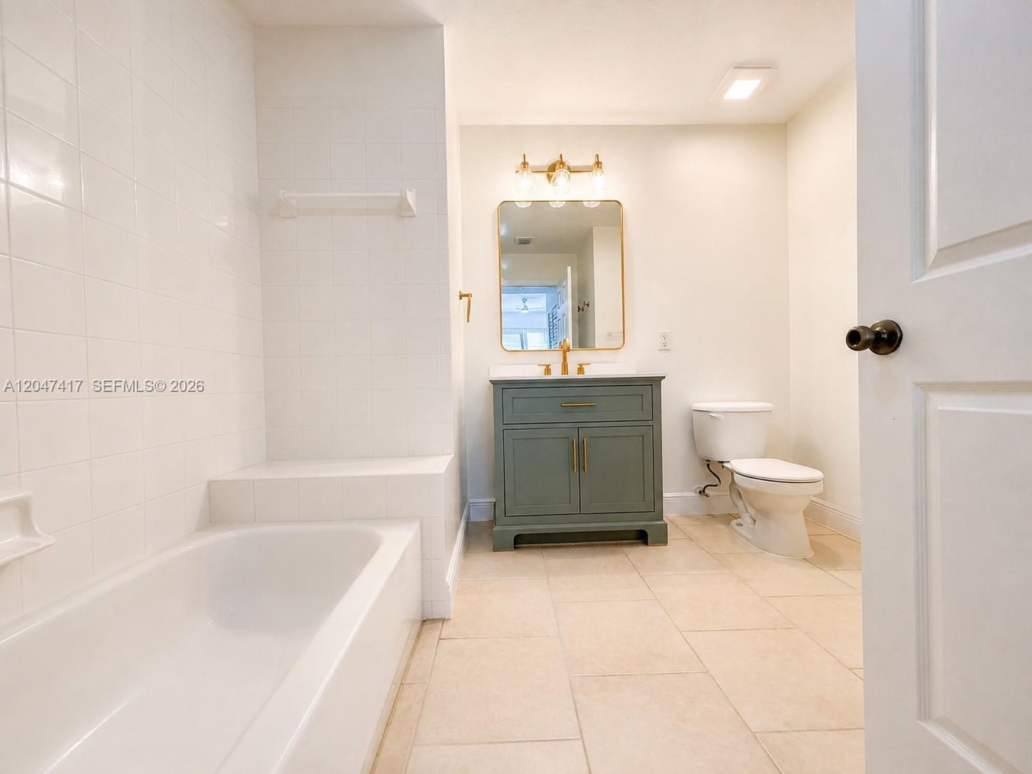 A bathroom features a green vanity, a gold-framed mirror, a toilet, and a tiled tub — 1203 Town Center # 314, Jupiter FL 33458, JUPITER, FL