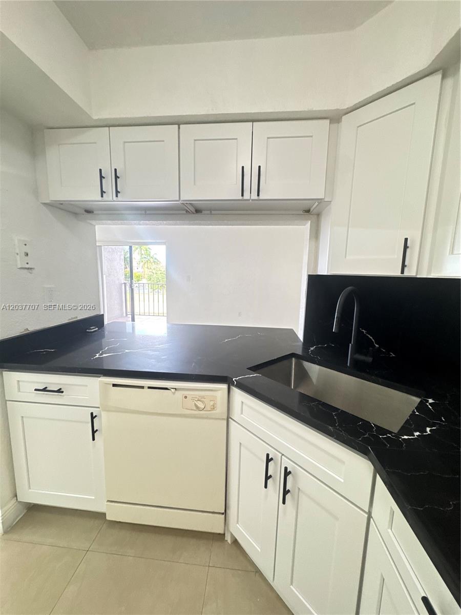 A kitchen features white cabinets, black countertops, a stainless steel sink, and a white dishwasher — 8500 NW 8th St # 303, Miami FL 33126, MIAMI, FL
