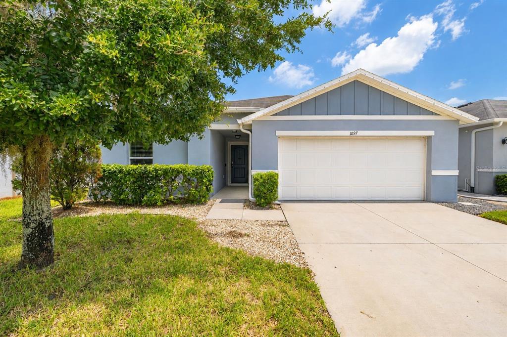 A single-story house with a blue exterior, a two-car garage, and a front lawn — 1097 AUGUSTUS DRIVE, DAVENPORT, FL