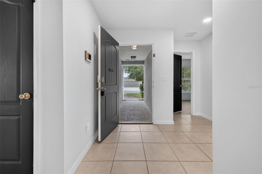 An entryway with beige tile flooring, a black front door, and a view of outdoors — 1097 AUGUSTUS DRIVE, DAVENPORT, FL
