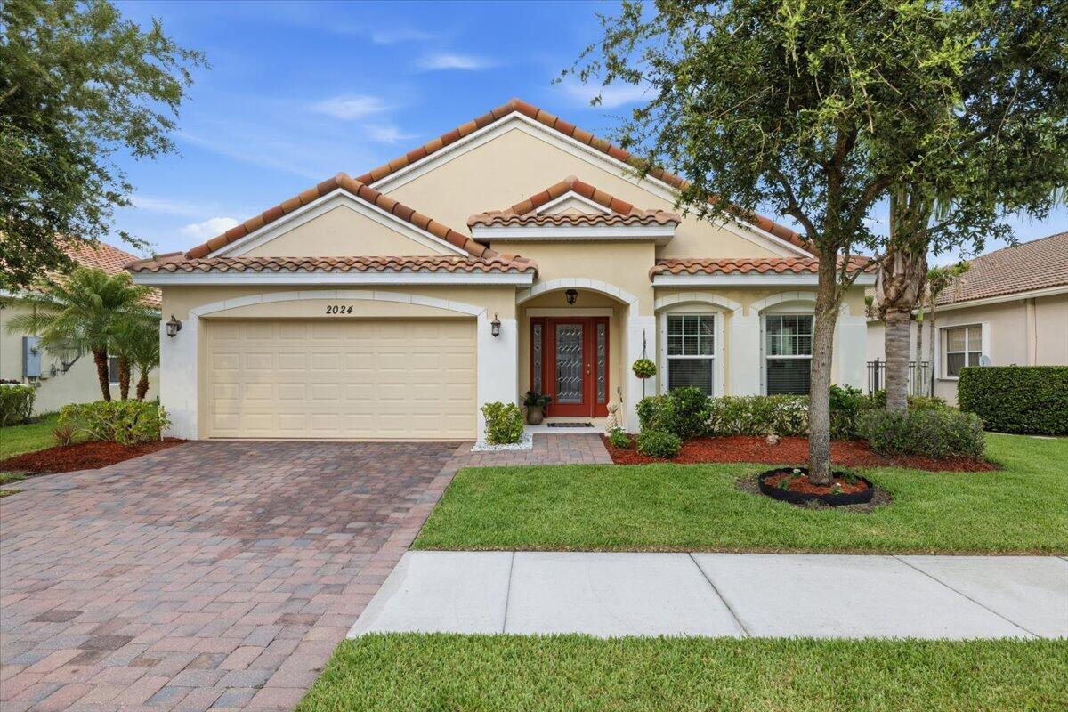A single-story house with a beige stucco exterior, red tile roof, and brick paver driveway — 2024 Albany Terrace SW, Vero Beach FL 32968, VERO BEACH, FL