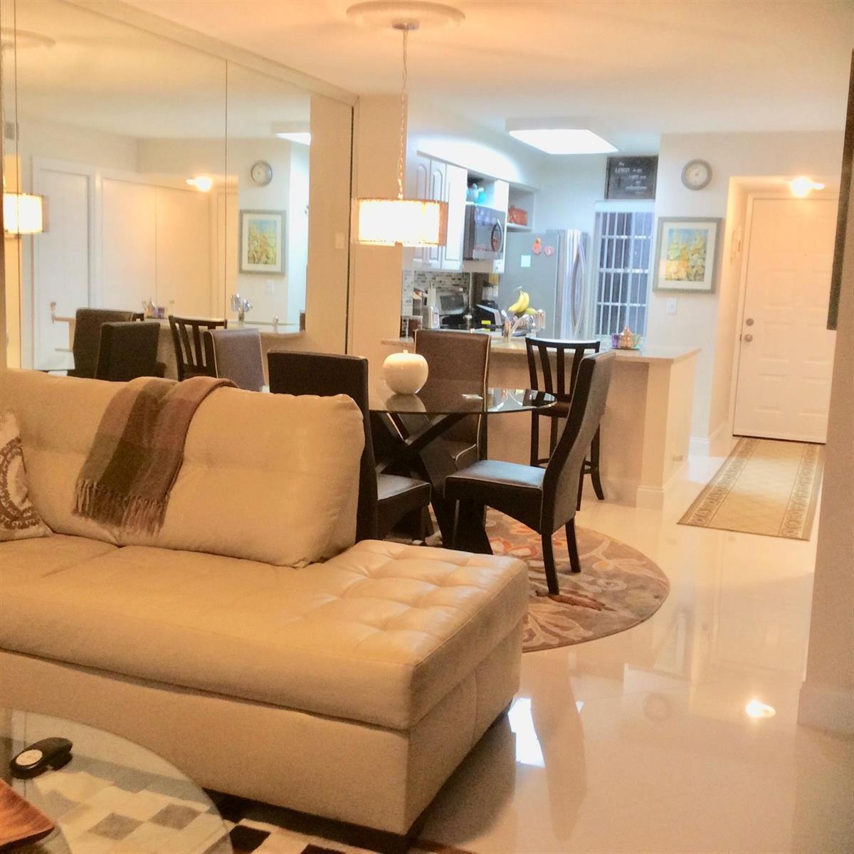 A living room with a beige sectional sofa, glass dining table, and mirrored wall — 2220 N Cypress Bend Drive # 104, Pompano Beach FL 33069, POMPANO BEACH, FL