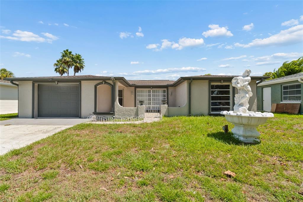 A single-story house with a garage, a front courtyard, and a decorative fountain in front — 7407 POPULUS DRIVE, PORT RICHEY, FL