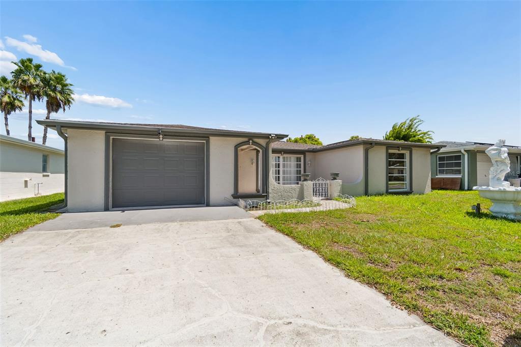 A single-story house with a gray garage door, a concrete driveway, and a front lawn — 7407 POPULUS DRIVE, PORT RICHEY, FL
