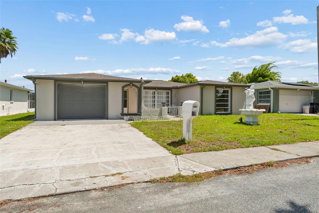 A single-story house with a gray garage, a white mailbox, and a front yard fountain — 7407 POPULUS DRIVE, PORT RICHEY, FL