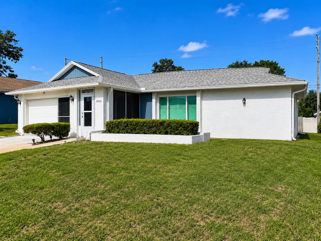 A single-story white house with a gray shingled roof and a green-shuttered front window — 2942 MACALPIN DRIVE W, PALM HARBOR, FL