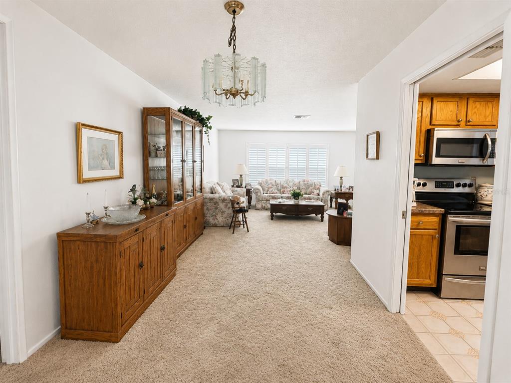 A living room features floral sofas, a wooden coffee table, and a large display cabinet — 2942 MACALPIN DRIVE W, PALM HARBOR, FL