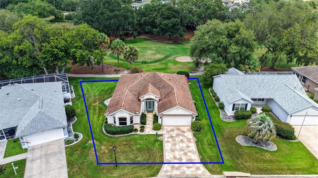 An aerial view shows a single-story house with a stone driveway and a blue outline — 522 LOMA PASEO DRIVE, LADY LAKE, FL