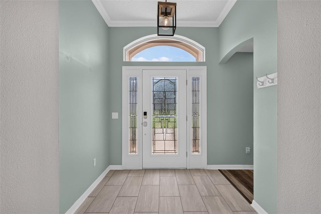 An entryway features a white front door with decorative glass, light blue walls, and tile flooring — 522 LOMA PASEO DRIVE, LADY LAKE, FL