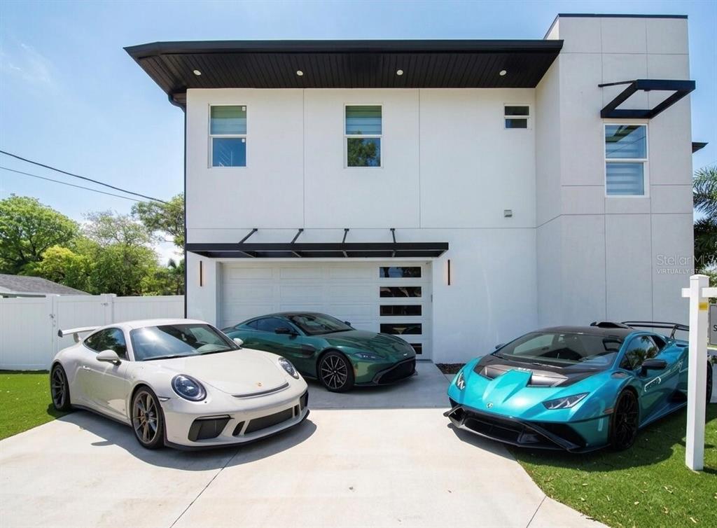 A modern two-story house with three luxury sports cars parked in the concrete driveway — 902 W SLIGH AVENUE, TAMPA, FL