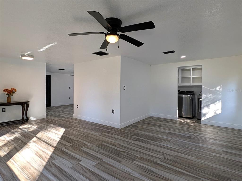 A bright room with wood-look tile flooring, a ceiling fan, and a laundry nook — 15217 BAILEY HILL ROAD, BROOKSVILLE, FL