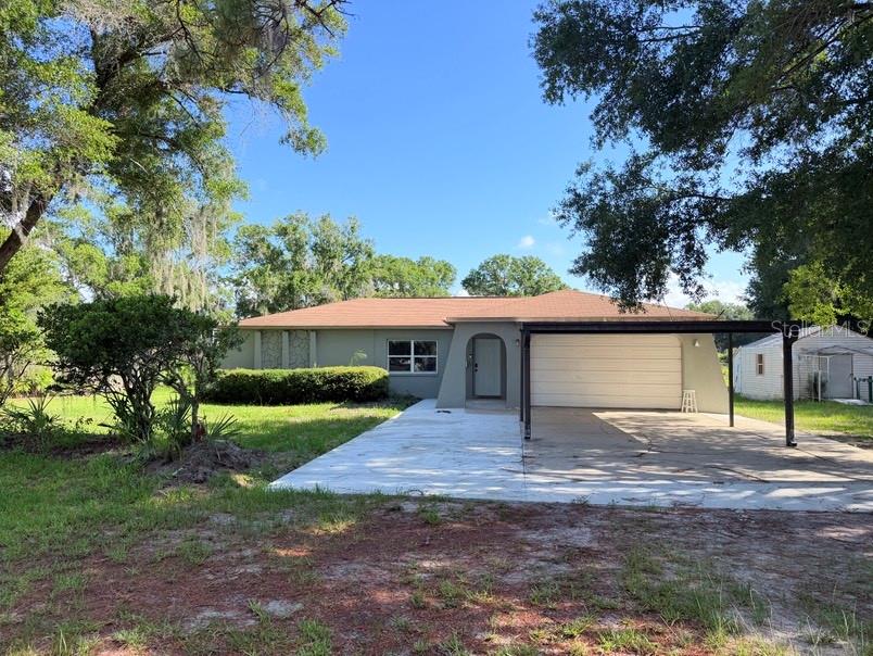 A single-story house with a brown roof, tan exterior, and an attached carport — 20801 CHISHOLM TRAIL, LAND O LAKES, FL