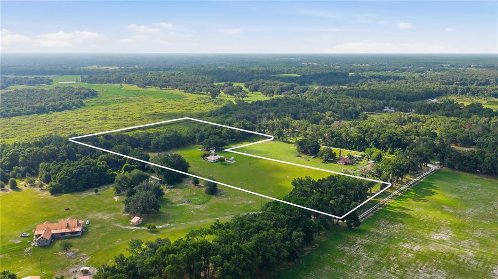 An aerial view shows a large, grassy rural property outlined in white with two houses — 6681 CR 665, BUSHNELL, FL