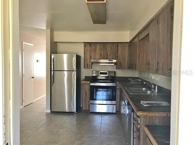 A kitchen features wood cabinets, stainless steel appliances, and tile flooring — 4139 OLD ROAD 37, LAKELAND, FL