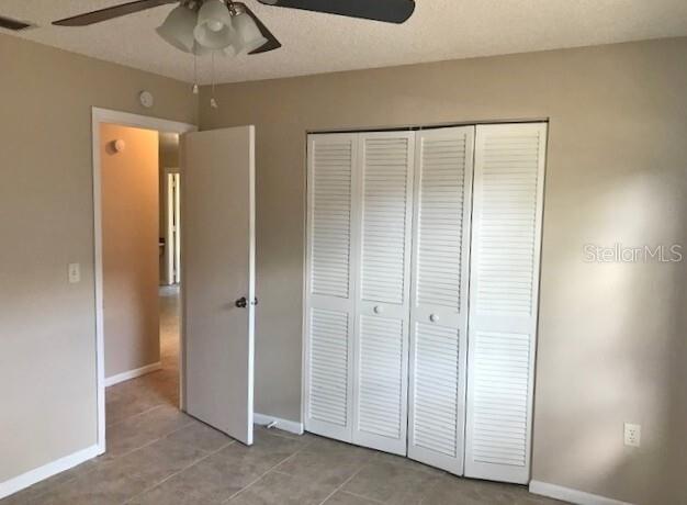 A bedroom features beige walls, tile flooring, a ceiling fan, and white louvered closet doors — 4139 OLD ROAD 37, LAKELAND, FL