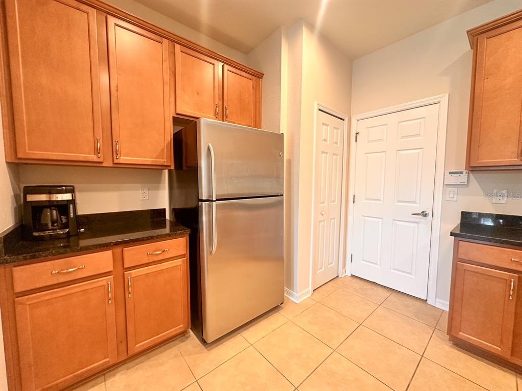 A kitchen features wooden cabinets, stainless steel appliances, dark countertops, and light-colored floor tiles — 11511 84TH STREET CIRCLE E UNIT 105, PARRISH, FL