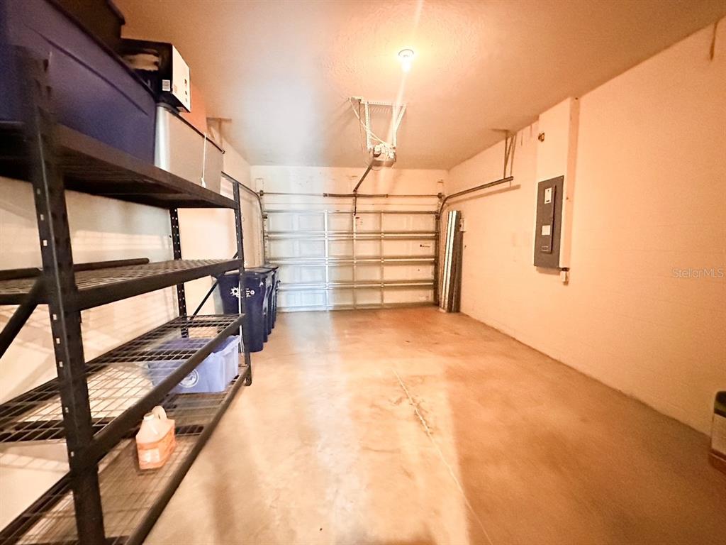 A garage with a concrete floor, metal shelving, and a white sectional garage door — 11511 84TH STREET CIRCLE E UNIT 105, PARRISH, FL