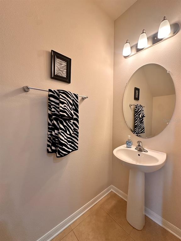 A small bathroom features a pedestal sink, an oval mirror, and a zebra-print towel — 11511 84TH STREET CIRCLE E UNIT 105, PARRISH, FL