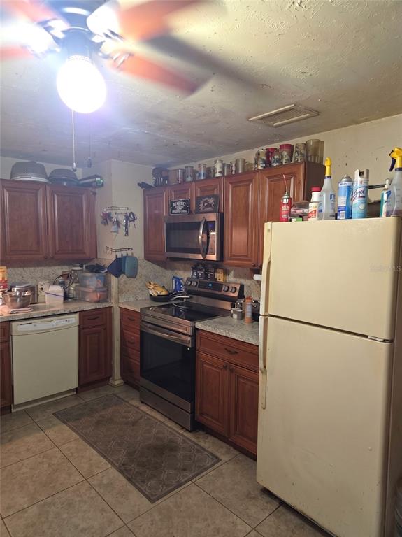 A kitchen features wood cabinets, stainless steel appliances, a tile floor, and a white refrigerator — 3539 COLLEEN DRIVE, LAKELAND, FL