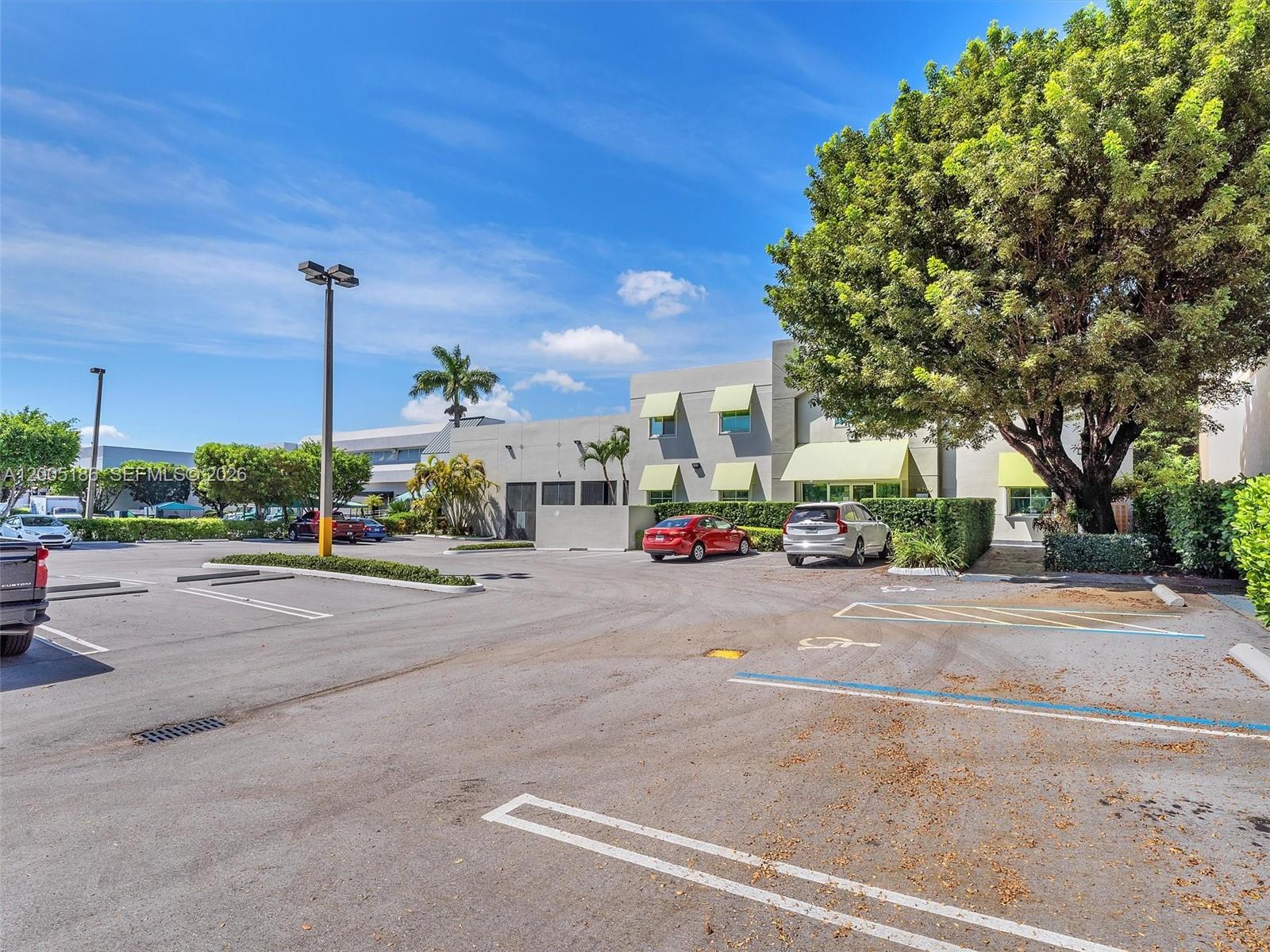A parking lot sits in front of a two-story commercial building with light green awnings — 8299 NW 30th Ter, Doral FL 33122, DORAL, FL