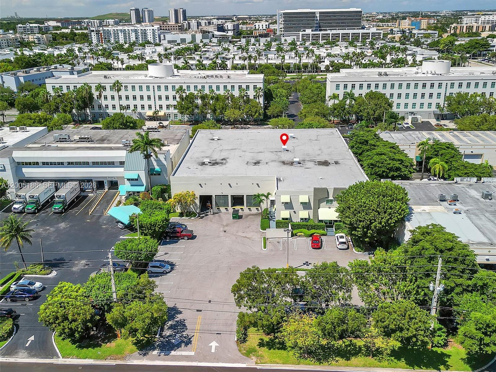 An aerial view shows a commercial building with a parking lot and surrounding landscaping — 8299 NW 30th Ter, Doral FL 33122, DORAL, FL
