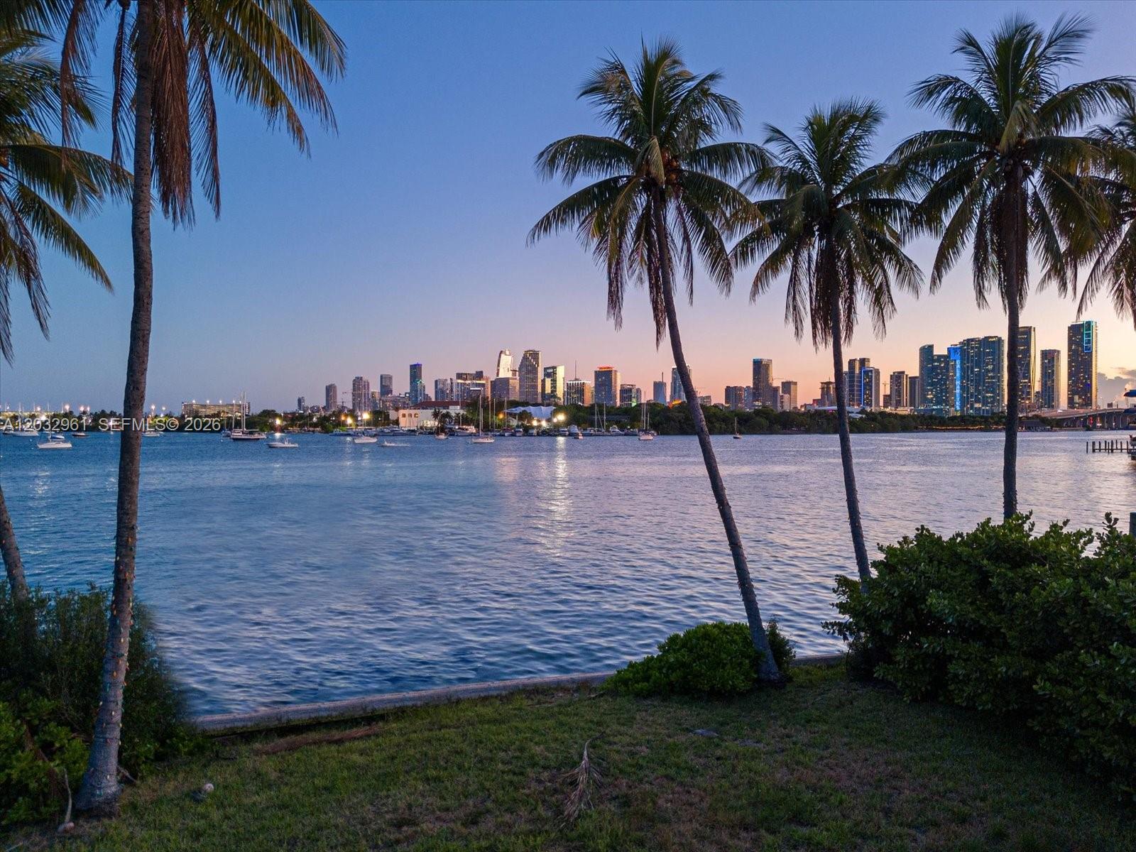 A view of a city skyline across a body of water with palm trees foreground — 1228 S Venetian Way, Miami FL 33139, MIAMI, FL