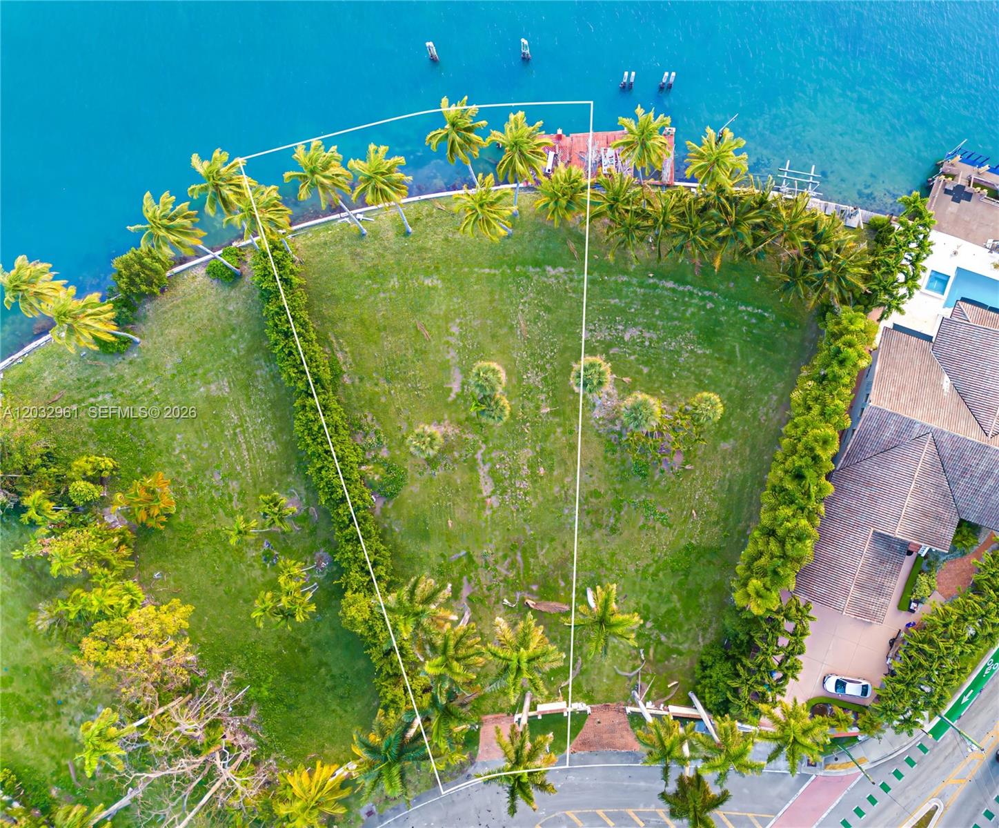 An aerial view shows a vacant, trapezoidal waterfront lot bordered by palm trees and hedges — 1228 S Venetian Way, Miami FL 33139, MIAMI, FL