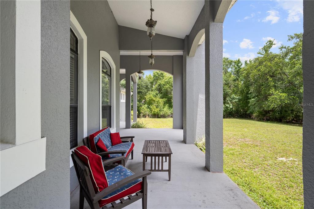 A covered concrete patio features two chairs with red cushions and a wooden coffee table — 5920 EDGERTON AVENUE, ORLANDO, FL