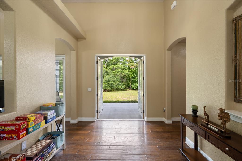 An entryway with wood floors, a game shelf, a console table, and open double doors — 5920 EDGERTON AVENUE, ORLANDO, FL