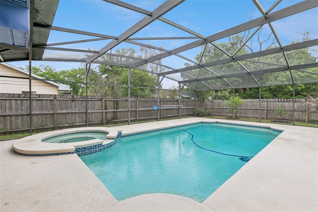 A screened-in swimming pool and attached hot tub sit on a concrete patio — 1711 CHARLESTON LANE, ST CLOUD, FL