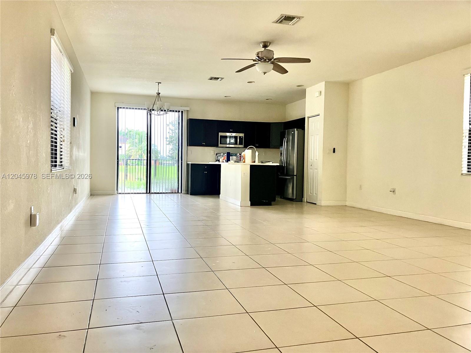An open-concept kitchen and living area features dark cabinetry, tile flooring, and a ceiling fan — 3797 NE 2nd St, Homestead FL 33033, HOMESTEAD, FL