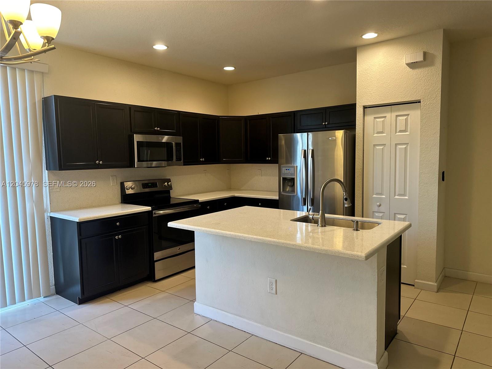 A kitchen features dark cabinets, light countertops, stainless steel appliances, and a central island — 3797 NE 2nd St, Homestead FL 33033, HOMESTEAD, FL