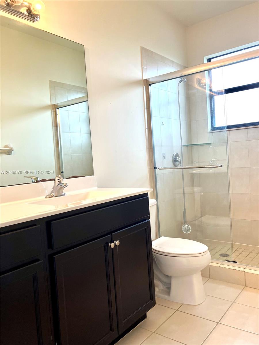 A bathroom features a dark vanity, a mirror, a toilet, and a glass-enclosed shower — 3797 NE 2nd St, Homestead FL 33033, HOMESTEAD, FL