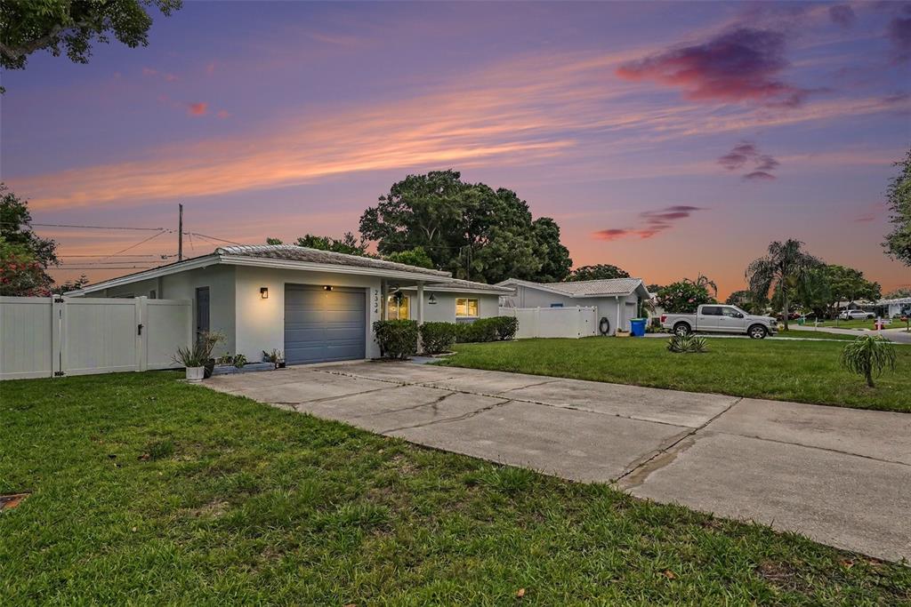 A single-story house with a gray garage and a concrete driveway at sunset — 2334 TUDOR LANE, CLEARWATER, FL